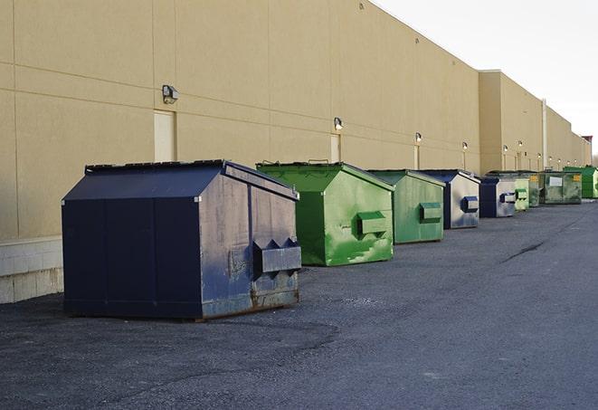 a construction worker unloading debris into a blue dumpster in Big Rock, IL